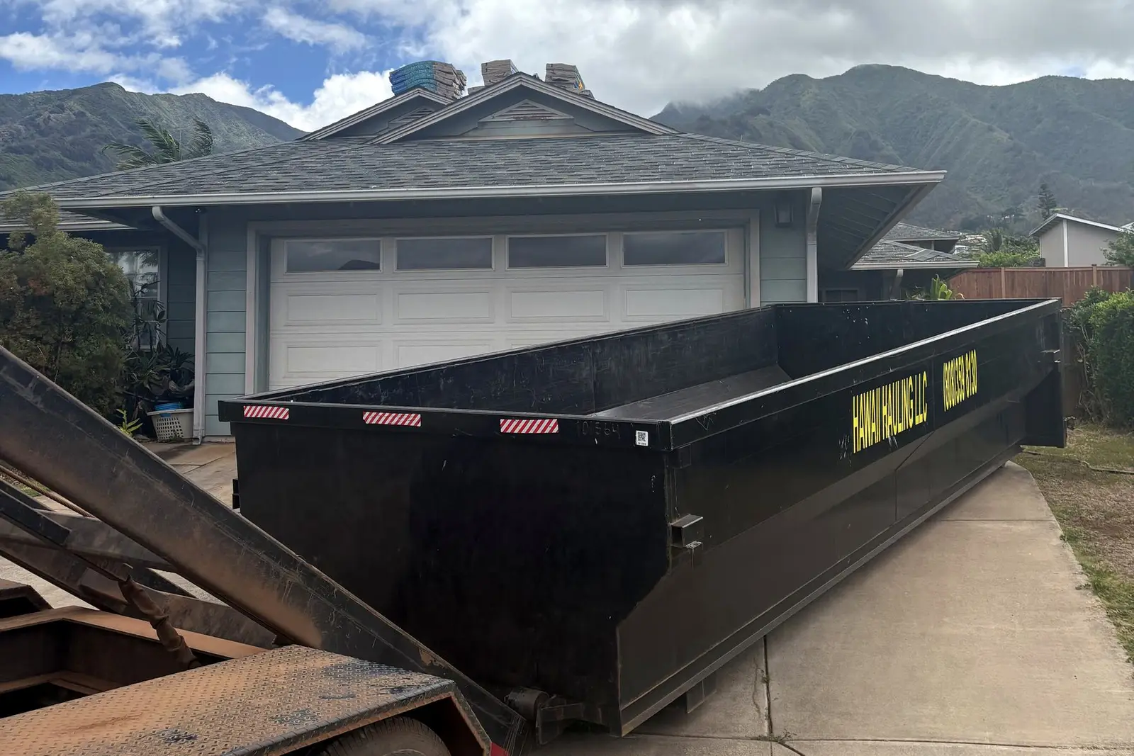 A Hawaii Hauling roll-off bin being dropped in a Maui driveway